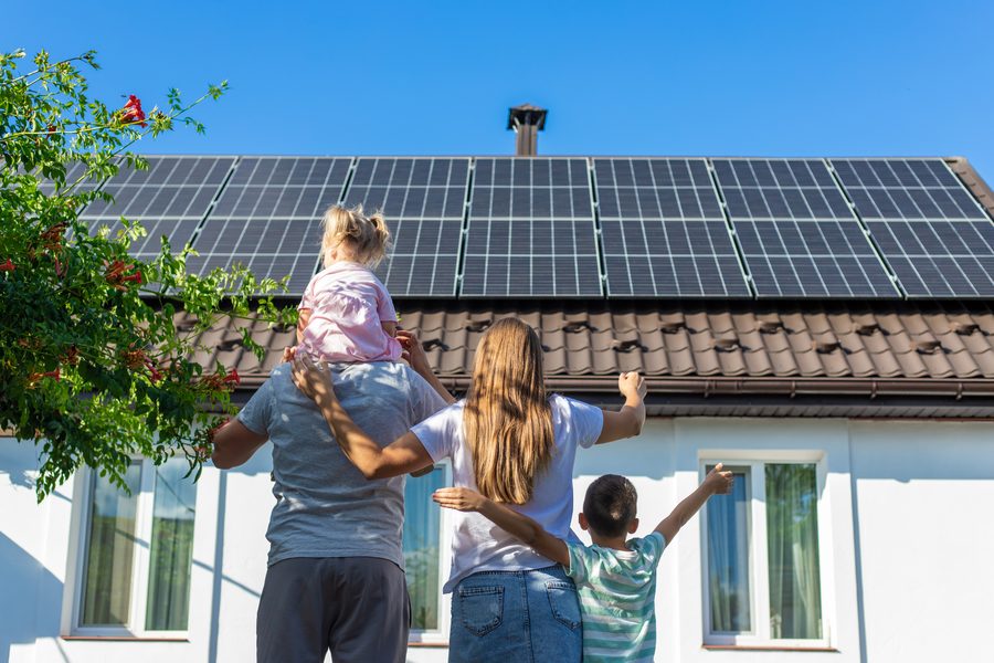 Família observando painéis solares instalados no telhado de casa